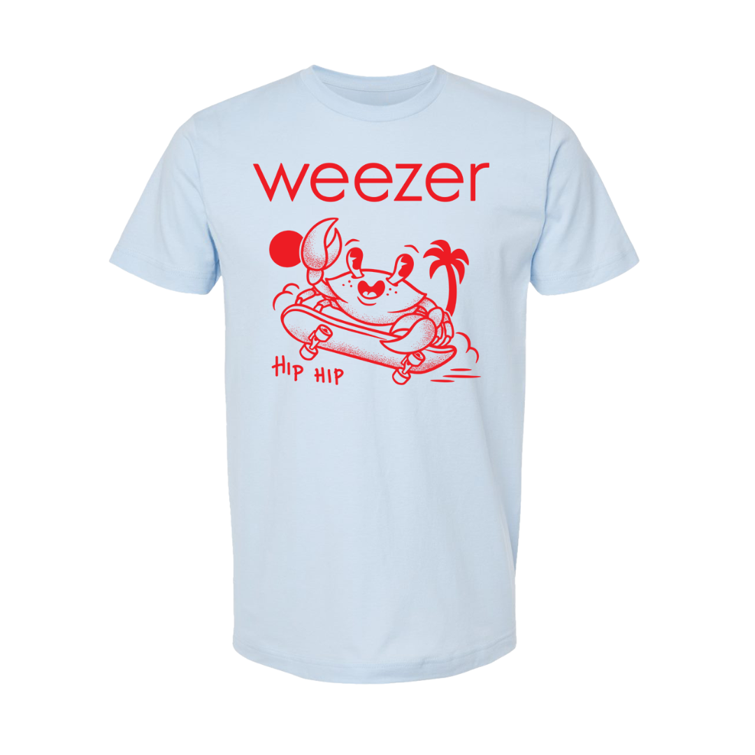 Light blue short-sleeved t-shirt featuring a red graphic of a crab on a skateboard with palm trees and the text ’weezer’ above it.