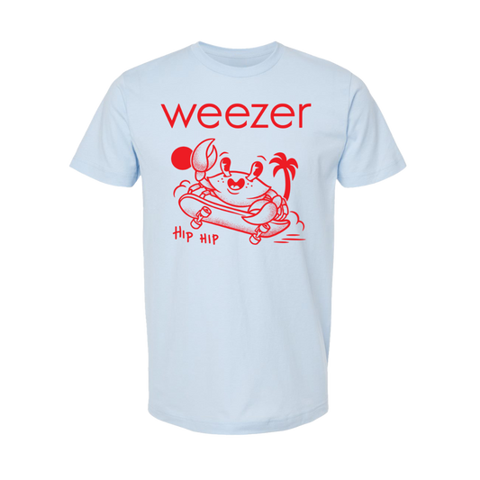 Light blue short-sleeved t-shirt featuring a red graphic of a crab on a skateboard with palm trees and the text ’weezer’ above it.